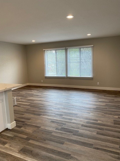 A room with wooden flooring and a window with blinds.